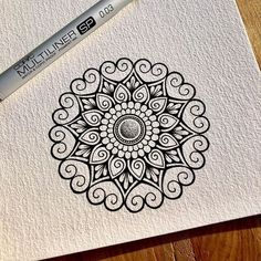 a pen is sitting on top of a piece of paper that has an intricate design