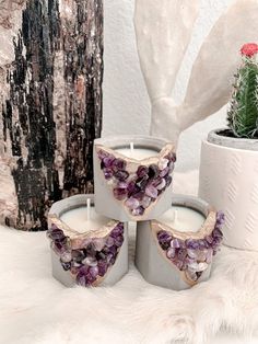 three candles with amethystal crystals on them next to a cacti