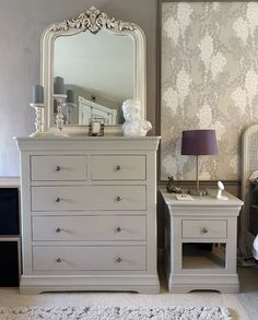 a white dresser sitting next to a bed in a bedroom