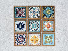 a group of nine colorful tiles mounted to the side of a white wall, each with different designs