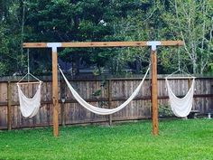 two hammocks hanging from a wooden structure in the backyard with grass and trees