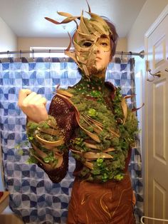 a man is dressed up as a creature in the bathroom with plants on his body