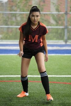 a female soccer player is standing on the field with her foot up and looking at the camera