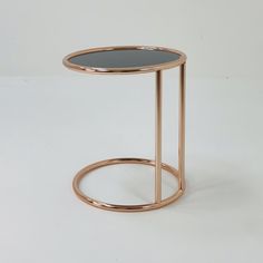 a round table with a metal frame and glass top, on a white surface in front of a plain background