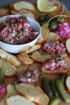 there is a bowl of food on top of crackers with pickles next to it