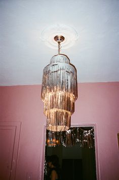 a chandelier hanging from the ceiling in a pink room