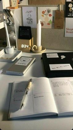 an open book sitting on top of a desk next to a pen and paper holder