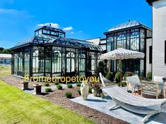 an outdoor area with chairs, tables and umbrellas in front of a building that has glass greenhouses on it