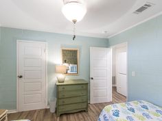 a bedroom with light blue walls and wooden floors