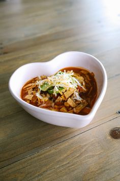 a heart shaped bowl filled with food on top of a wooden table