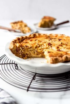 a pie sitting on top of a white plate next to a rack with slices missing