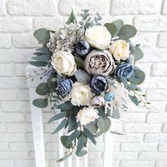 a bridal bouquet sitting on top of a white chair next to a brick wall