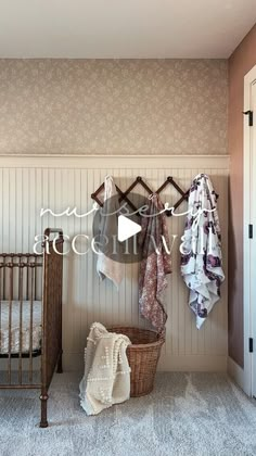 a baby's crib in the corner of a room with clothes hanging on hooks