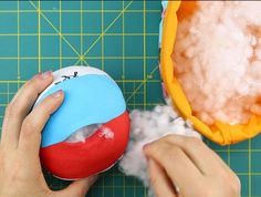 someone is decorating an easter egg with foam and cotton on a cutting board next to it