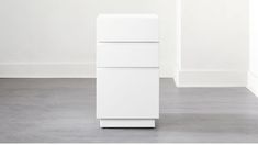 a tall white cabinet sitting on top of a cement floor next to a wall in an empty room