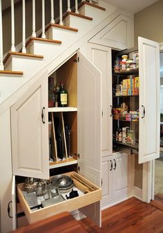 an under the stairs kitchen storage area with drawers and cupboards open to reveal food items