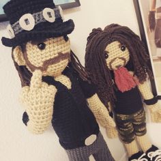 two crocheted dolls standing next to each other on a wall in front of a mirror