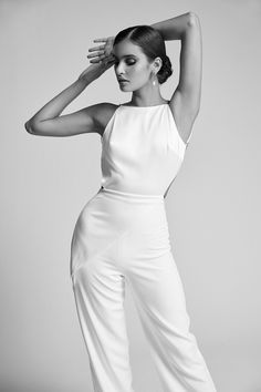 a woman in white is posing with her hands on her head