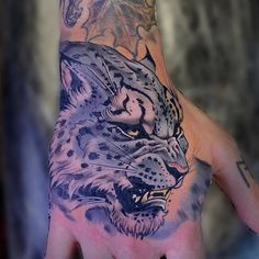 a man's hand with a tattoo of a leopard on it and an eagle in the background