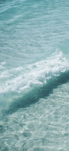 a man riding a surfboard on top of a wave in the ocean next to shore