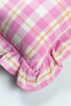 a pink and orange checkered pillow on a white surface