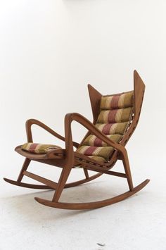 a wooden rocking chair with striped seat and back cushions on the bottom, in front of a white wall