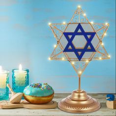 a star of david on a table with donuts and candles in front of it