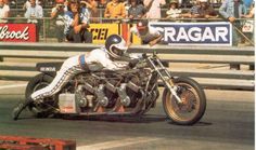 a man riding on the back of a motorcycle down a race track in front of a crowd