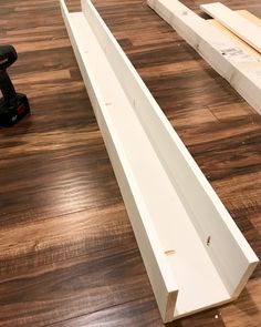 two pieces of wood sitting on top of a hard wood floor next to a power drill