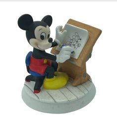 a mickey mouse figurine sitting on top of a table next to an easel