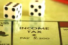 two dices sitting on top of a monopoly board with the words, income tax written on it