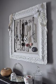 a white frame with lots of necklaces hanging on it's wall next to a basket