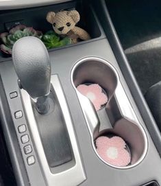 an automatic gear box with two cup holders and a teddy bear in the center console