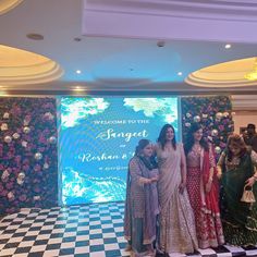 four women standing in front of a backdrop with flowers