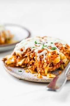 a plate topped with lasagna covered in sauce and cheese next to a fork