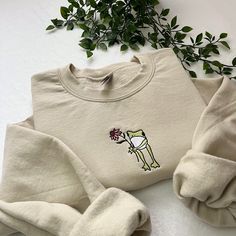 ✿ Flower Frog Embroidered Sweatshirt 🐸🌸 - ✿ Frog with flower embroidered on a unisex sweatshirt! an amazing gift idea!  - ✿ This design can be done on different coloured sweatshirts and with different coloured thread, as well as on totes, t-shirts and hoodies so please message me if you'd like to personalise it!  - ✿ Please look at the last slide for the size guide! I do not accept returns if you pick the wrong size, so please make sure you choose the correct one!  - ✿ I have lots of other ite Embroidered Clothes Ideas, Hoodie Embroidery Ideas, Embroidery Sweatshirt Ideas, Sweatshirts Ideas, Embroidery Sweaters, Embroidered Frog, Frog Embroidery, Frog Sweatshirt, Colorful Sweatshirt