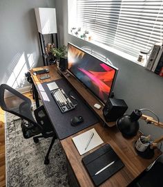 a desk with a computer monitor, keyboard and mouse on it in front of a window