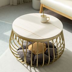 a coffee table with a cup on top and pillows under the table in front of it