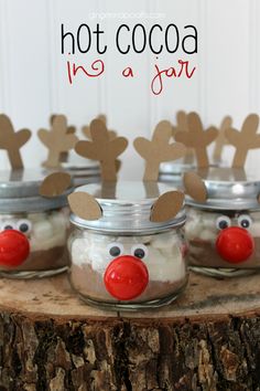 four mason jars decorated with reindeer noses and red nose, sitting on top of a tree stump