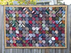 a quilt is hanging on a wooden fence