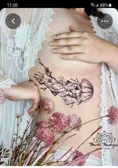 a woman with tattoos on her stomach and flowers in front of her belly, while holding the