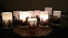 five lit candles sitting on top of a doily with city skylines in them