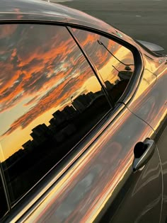 a reflection of the sky and clouds in a car's side window is shown