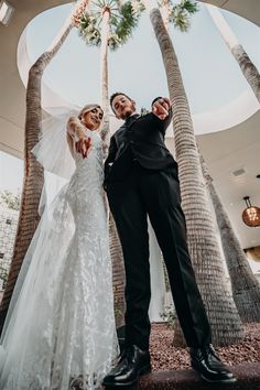 a newly married couple standing under palm trees