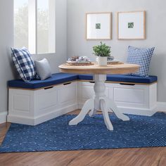 a corner table with two blue cushions on it and a bench in the middle for seating