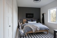 a bedroom with black and white striped flooring, gray bedding and wooden headboard