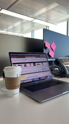 an open laptop computer sitting on top of a desk next to a cup of coffee