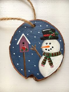 a wooden ornament with a snowman and birdhouse on it's side