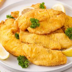 fried fish with parsley and lemon slices on a white plate, ready to be eaten