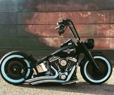 a black and blue motorcycle parked in front of a wall with graffiti painted on it